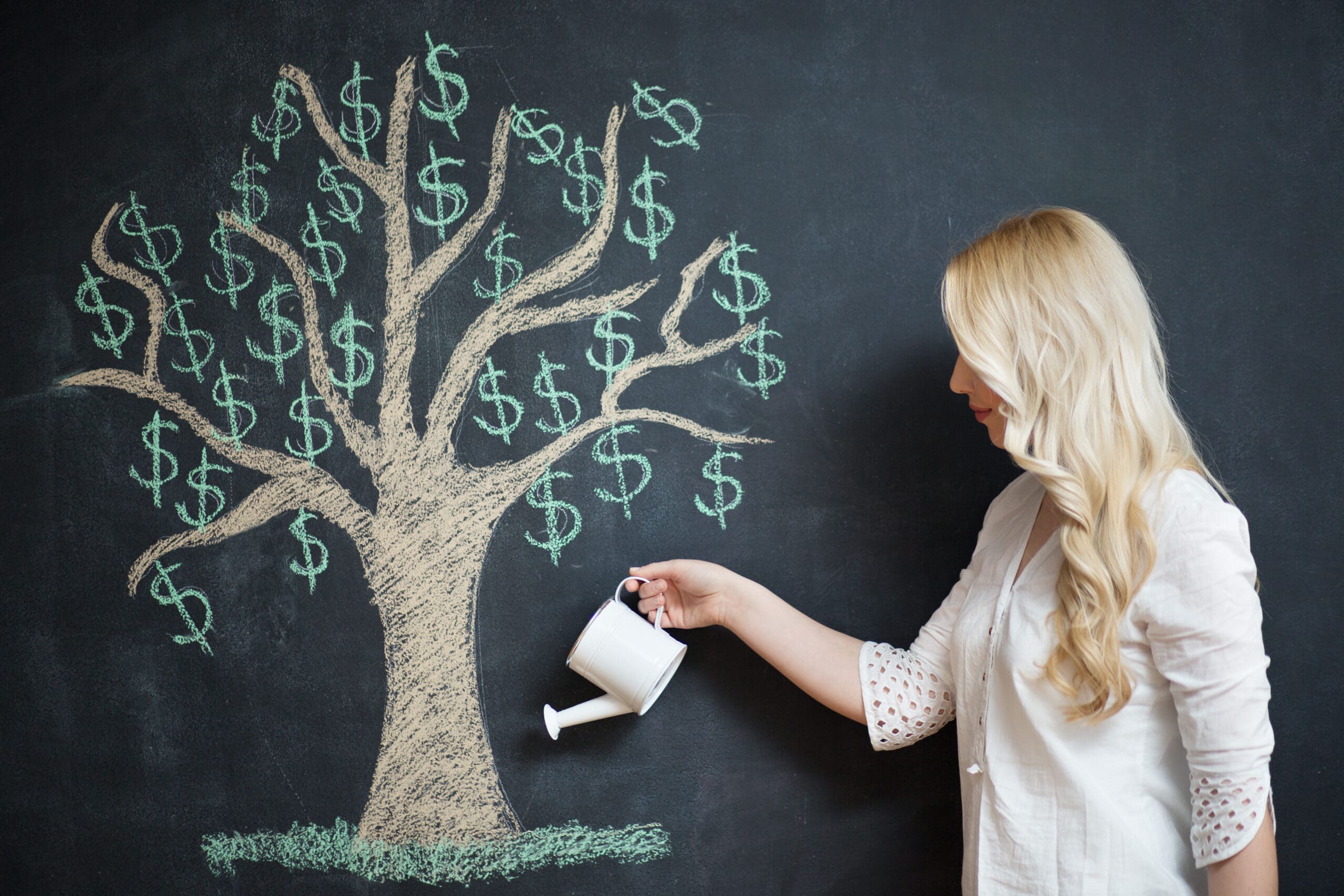A woman holds a watering can and pretends to water a tree with dollar signs drawn on a chalkboard.