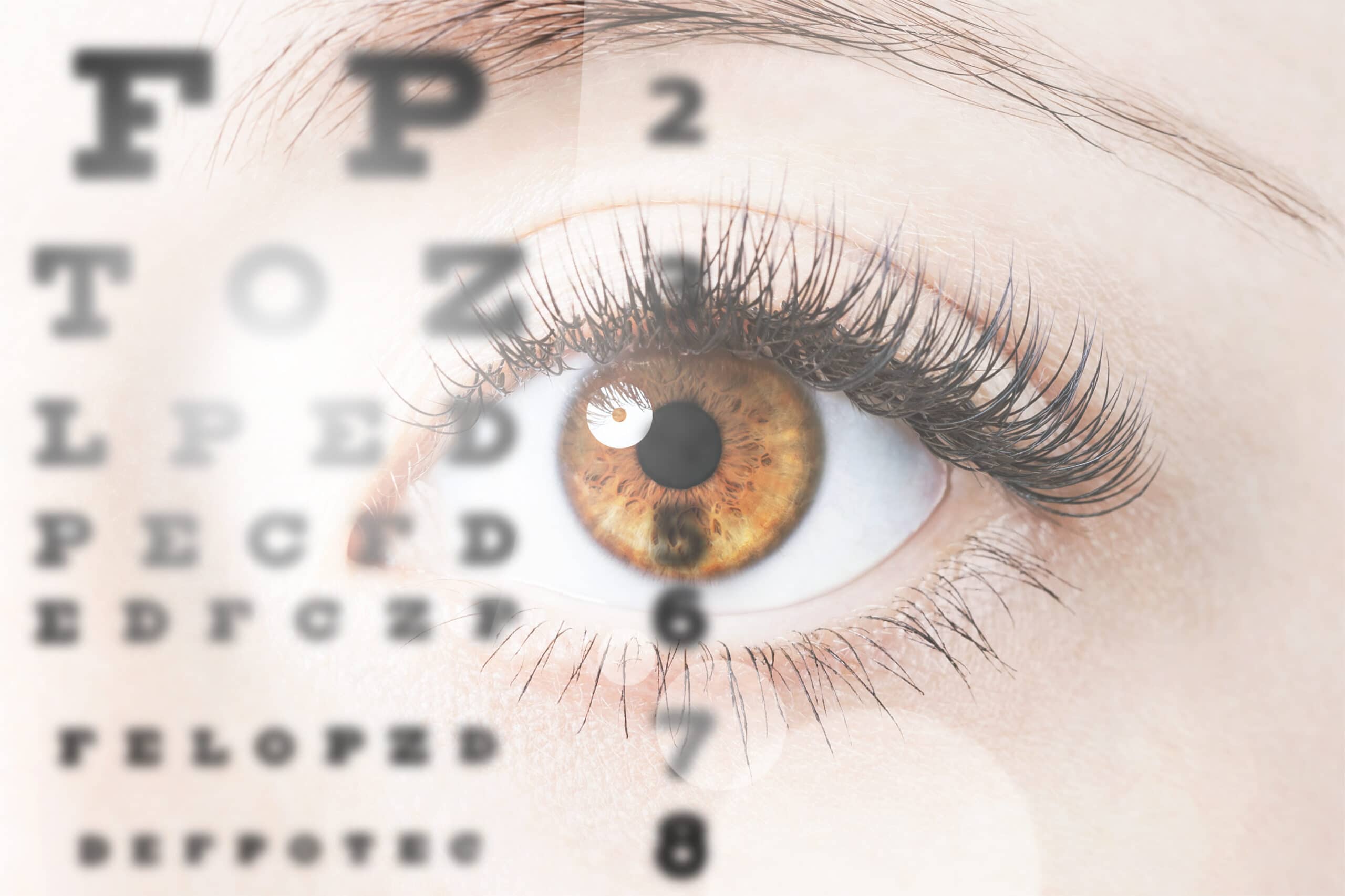 Close-up of a brown eye with long eyelashes, overlaid with a blurred eye chart used for vision tests.