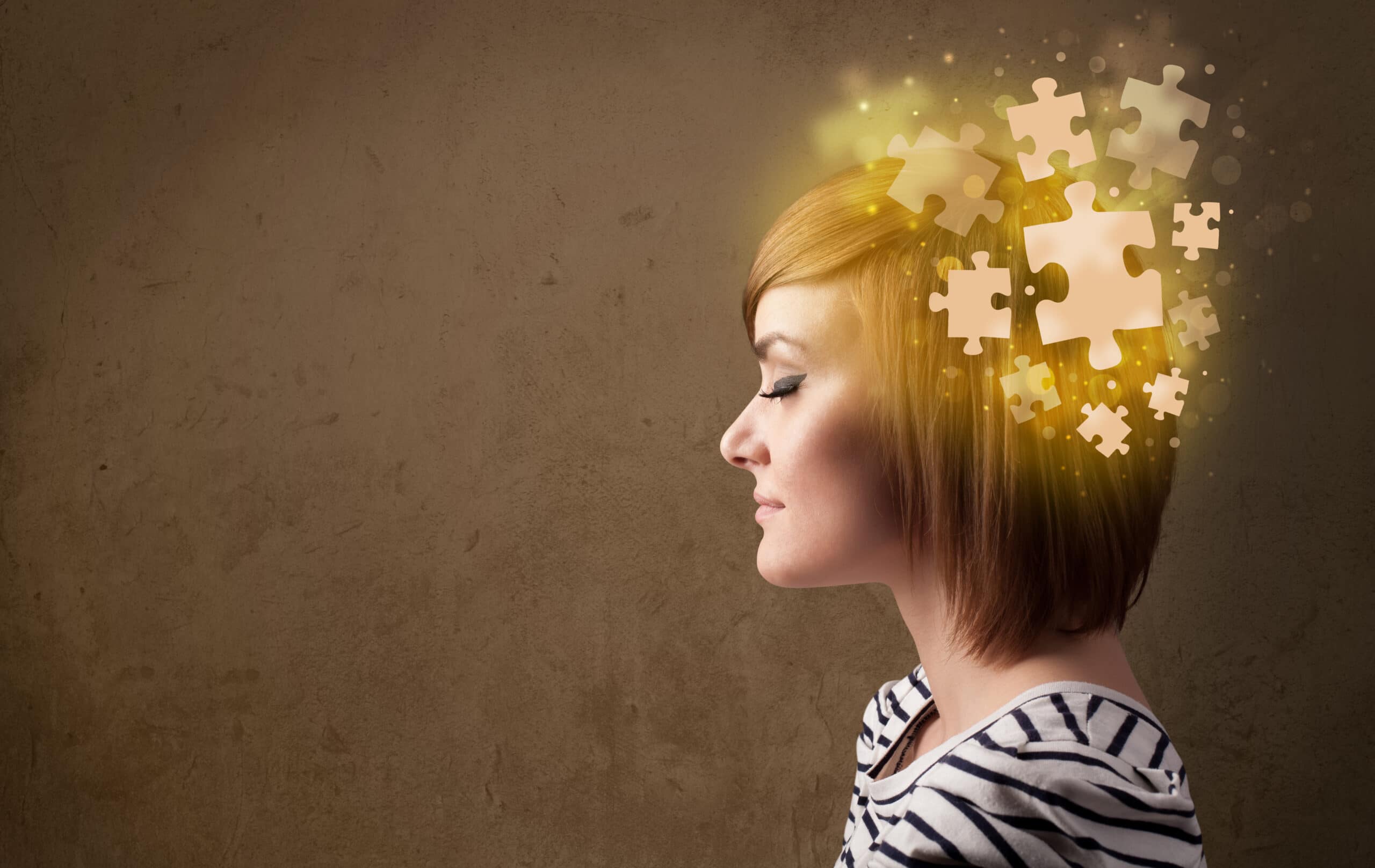 A woman in a striped shirt with her eyes closed, with glowing puzzle pieces emanating from her head, symbolizing thoughts or mental processes.