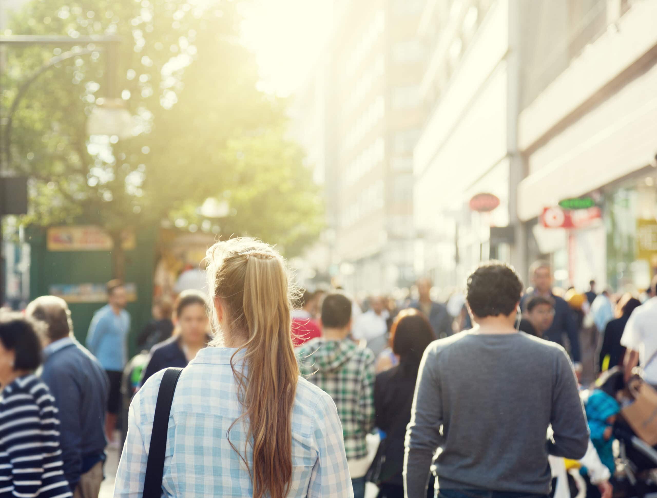 A busy city street filled with people walking in both directions on a sunny day.