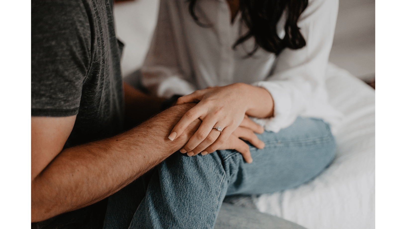 Two people sit close together on a bed, one wearing a ring and gently holding the other’s arm, reflecting real marriage advice for LDS couples about support and intimacy.