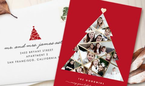 A Christmas card with a white tree photo collage on a red background is shown next to an addressed envelope with a holiday stamp and dried leaves.