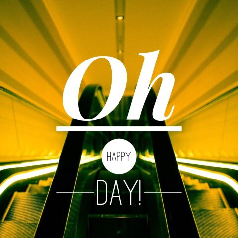 Yellow-lit escalator with the words "Oh HAPPY DAY!" in bold white text overlaying the image.