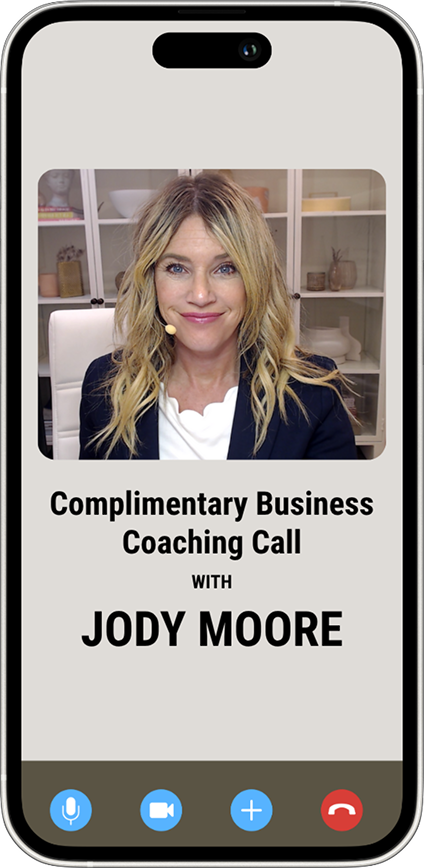A woman sits in an office setting during a video call. Text on the screen reads, “Complimentary Business Coaching Call with Jody Moore.”.