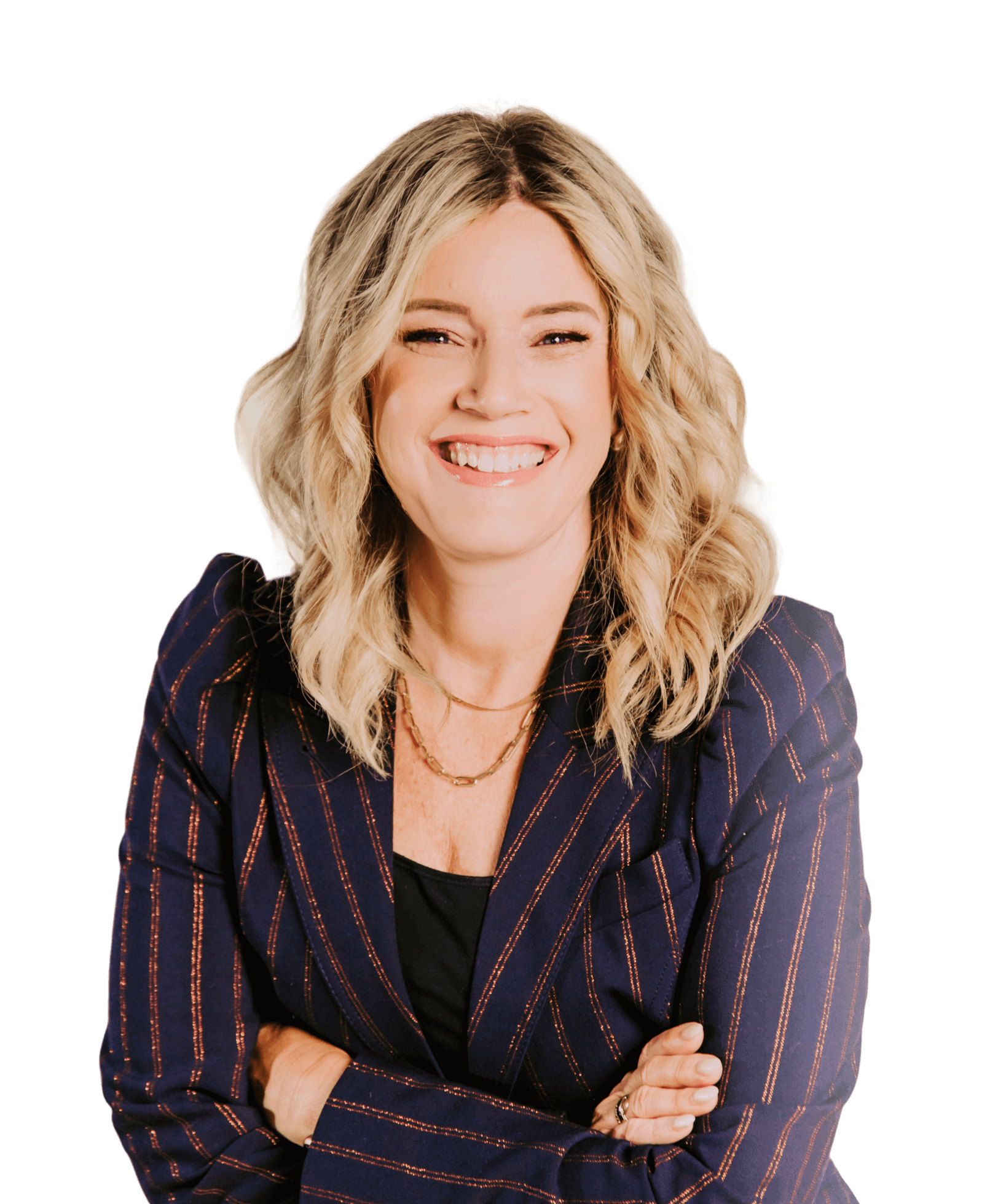 A woman with wavy blonde hair, wearing a navy pinstripe blazer and black shirt, smiles with her arms crossed against a plain black background.